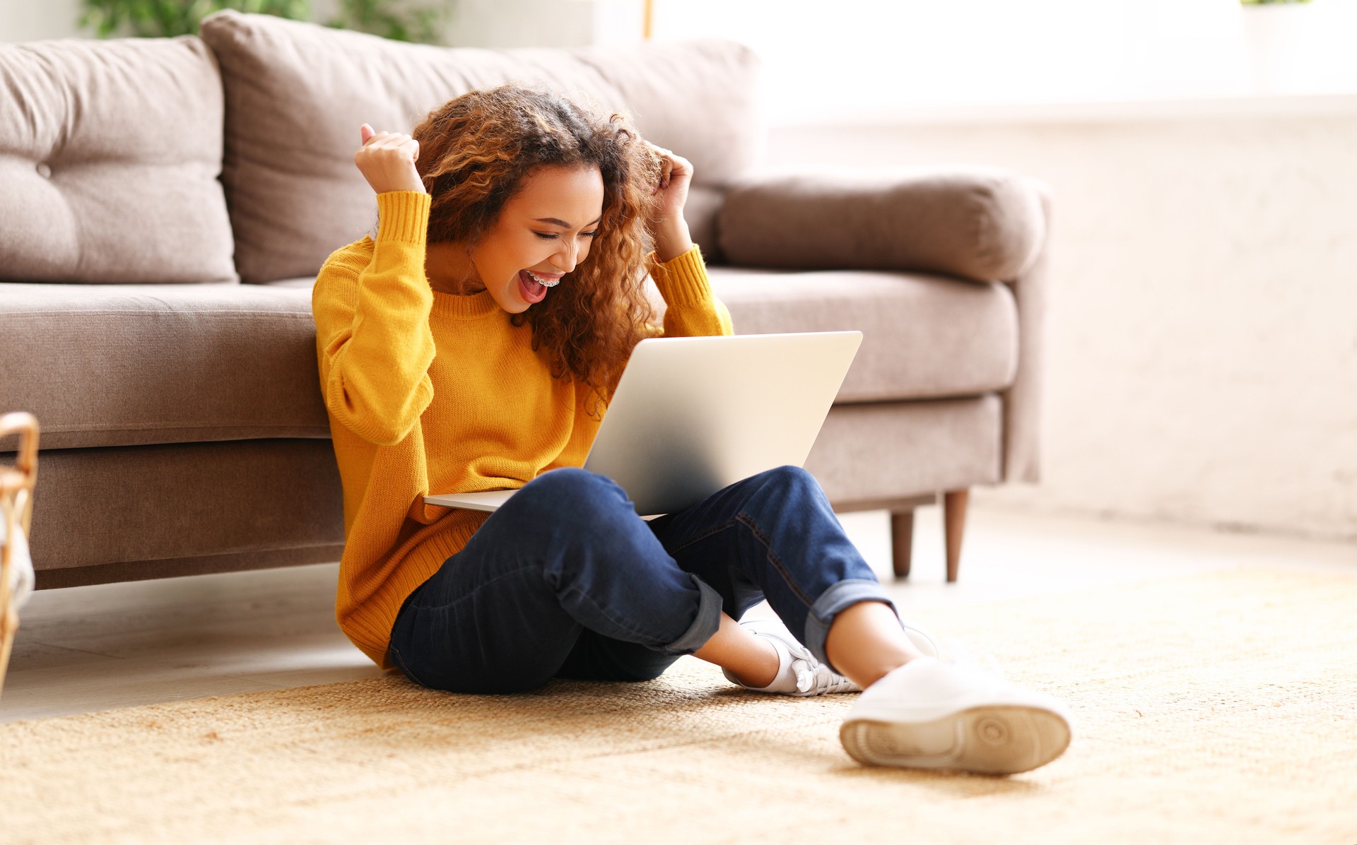 Happy african american female celebrating success while working remotely or studying online at home