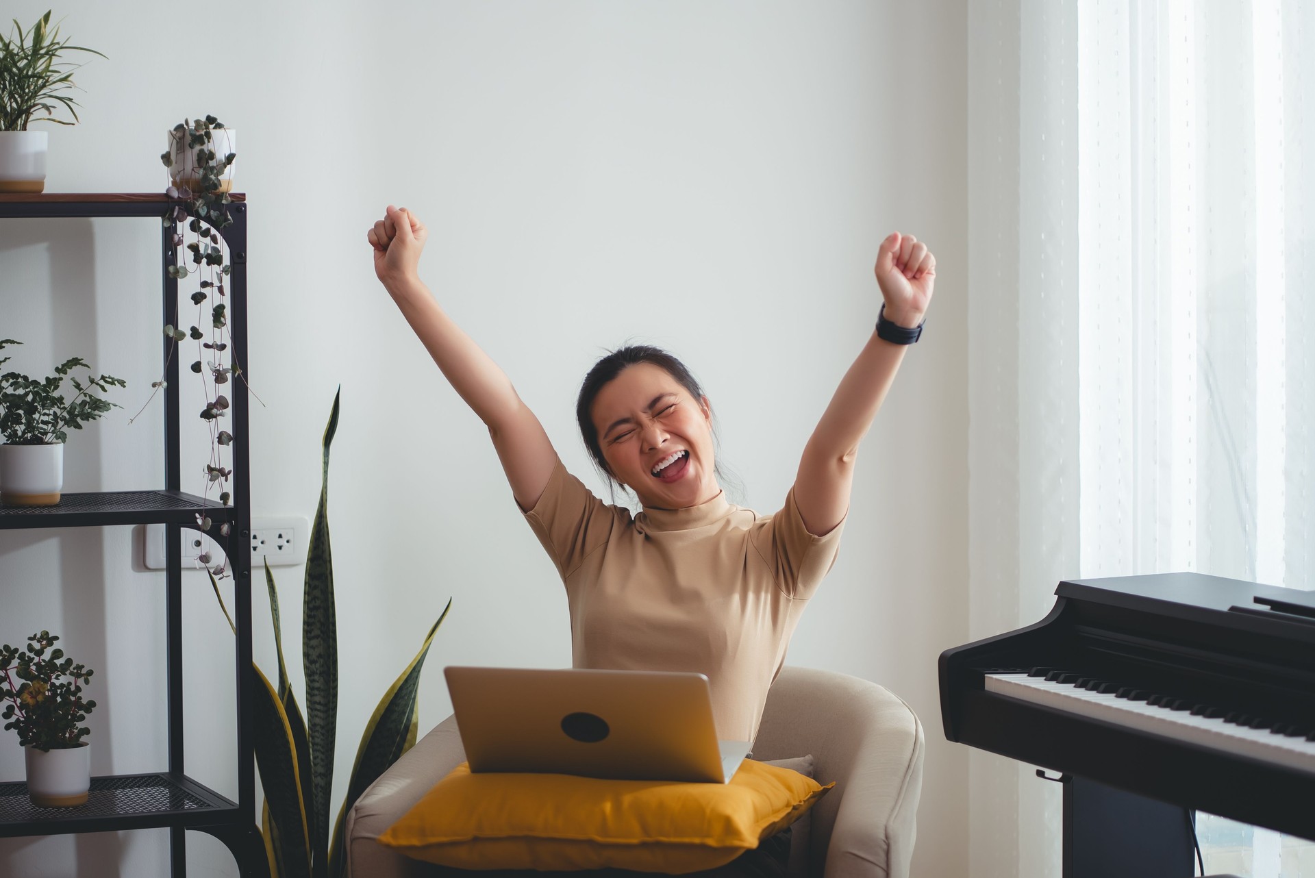 Asian woman using laptop happy excited making a winning gesture sitting in living room at home.